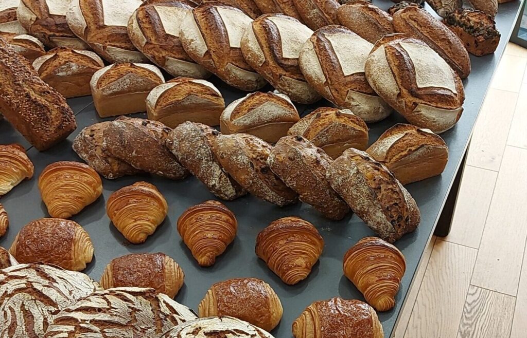 Assortiment de pains et de viennoiseries artisanales disposés sur une table en bois.